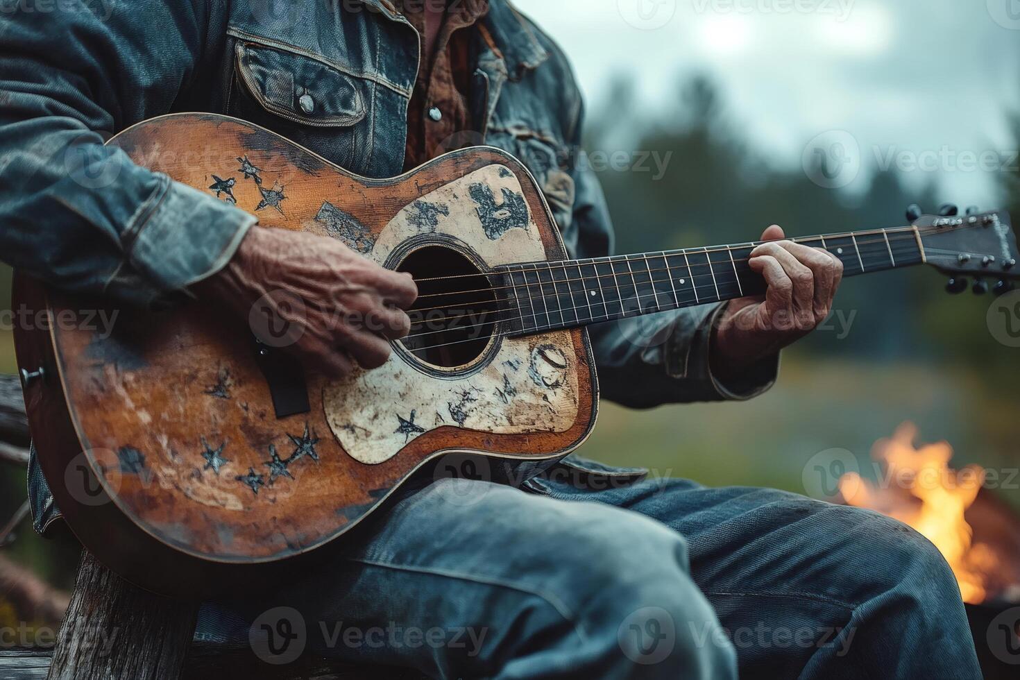 Musician playing acoustic guitar outdoors by bonfire photo