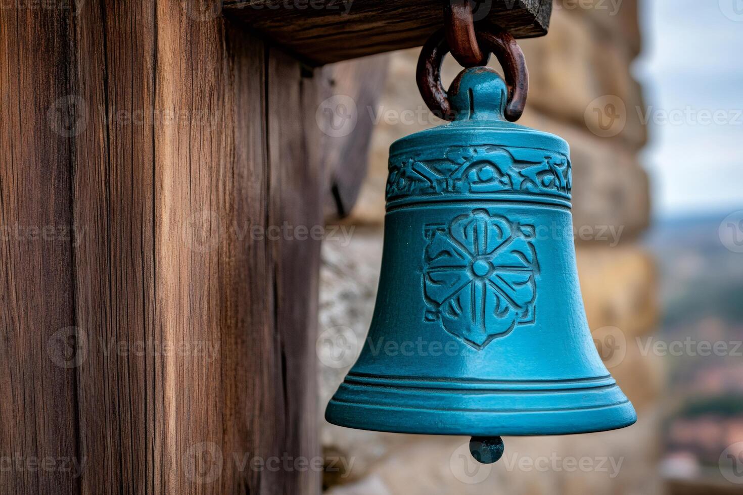 Turquoise metal bell hanging on wooden beam in rustic setting photo