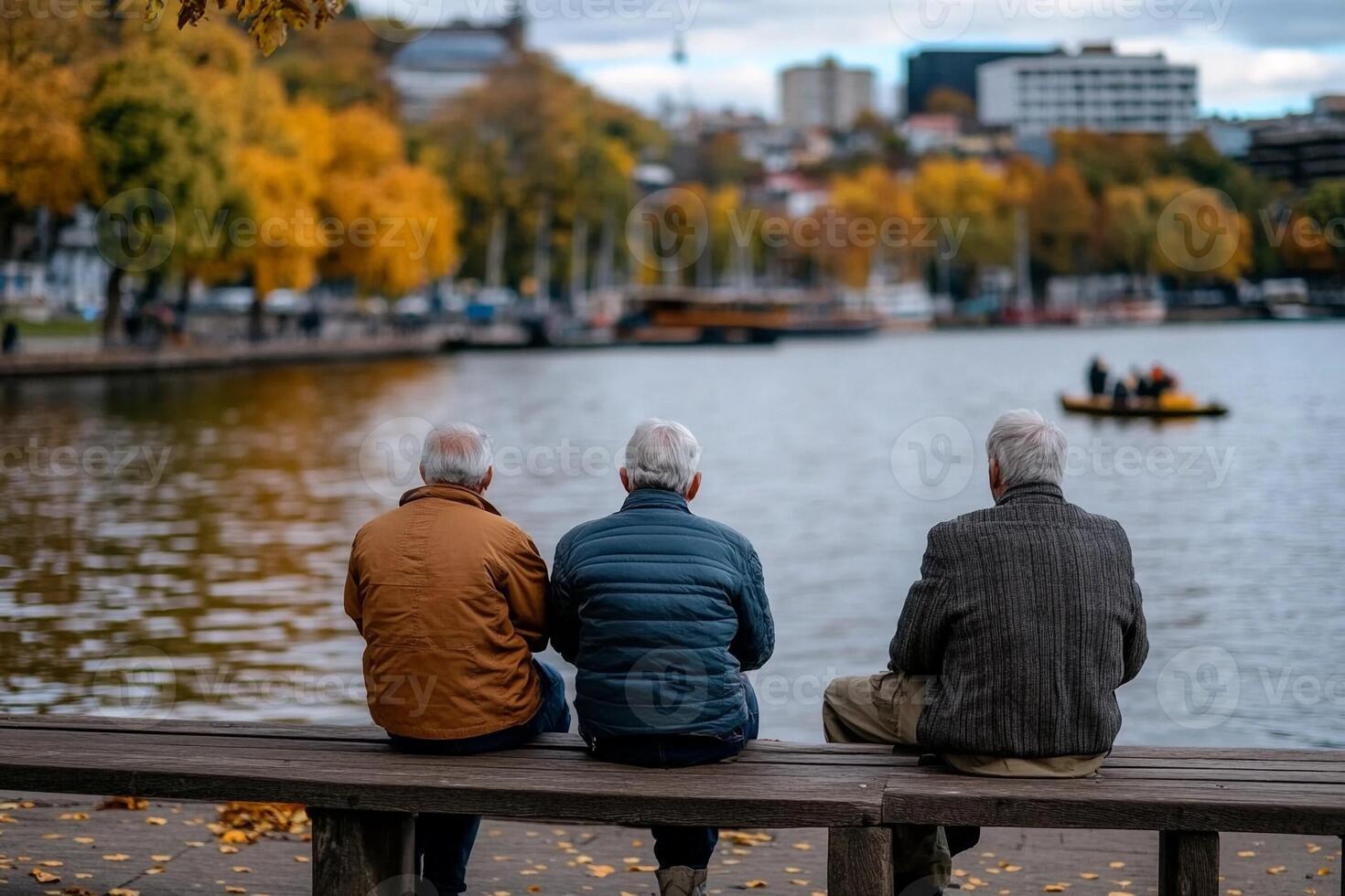 Three older men sitting on a bench overlooking a lake photo