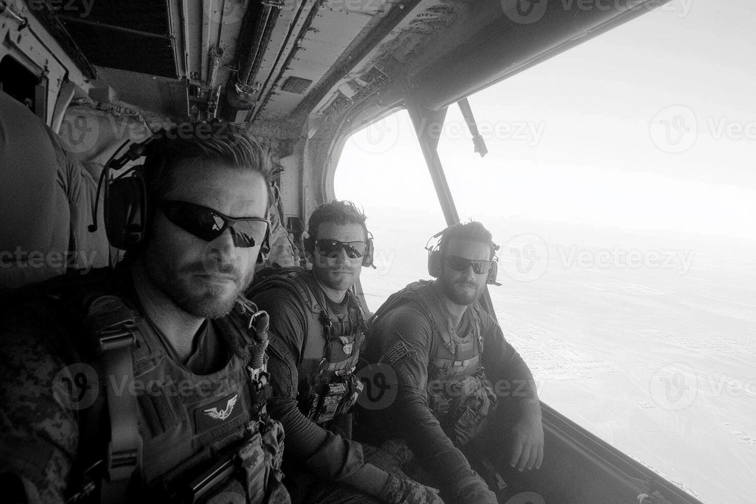 Three men in military gear sitting in the cockpit of a helicopter photo