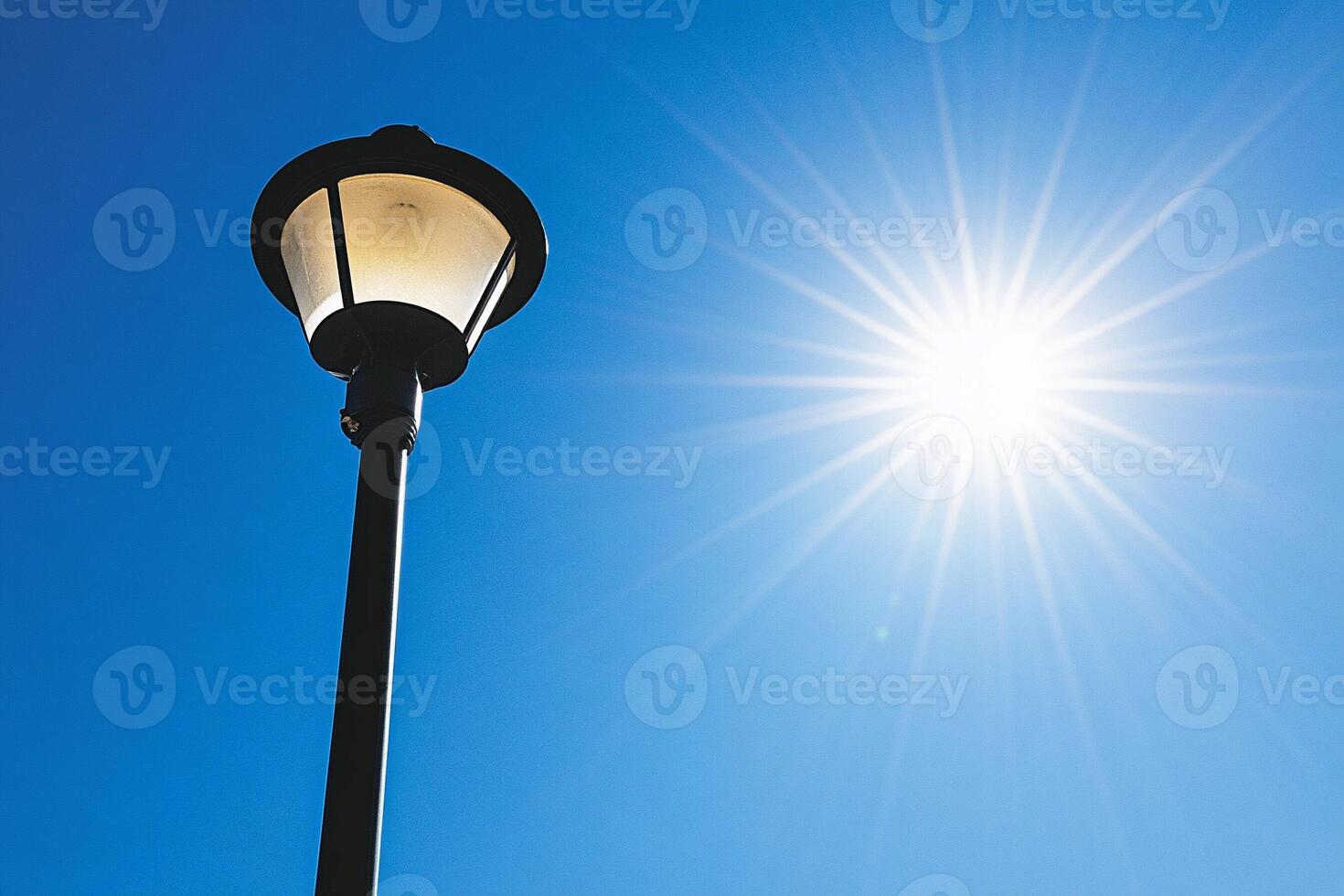 A street light with a sun shining through the blue sky photo