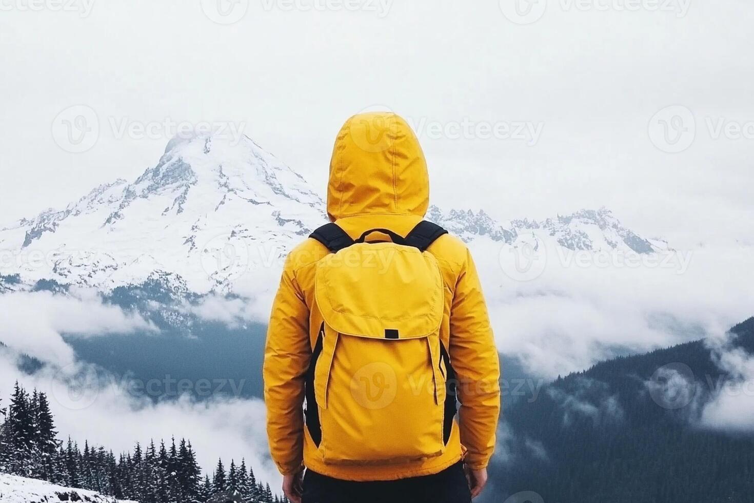 A person with a yellow backpack standing on top of a mountain photo