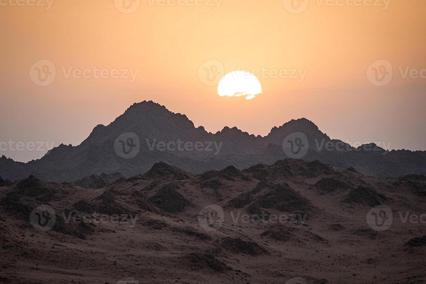 The sun sets over the mountains in the desert photo