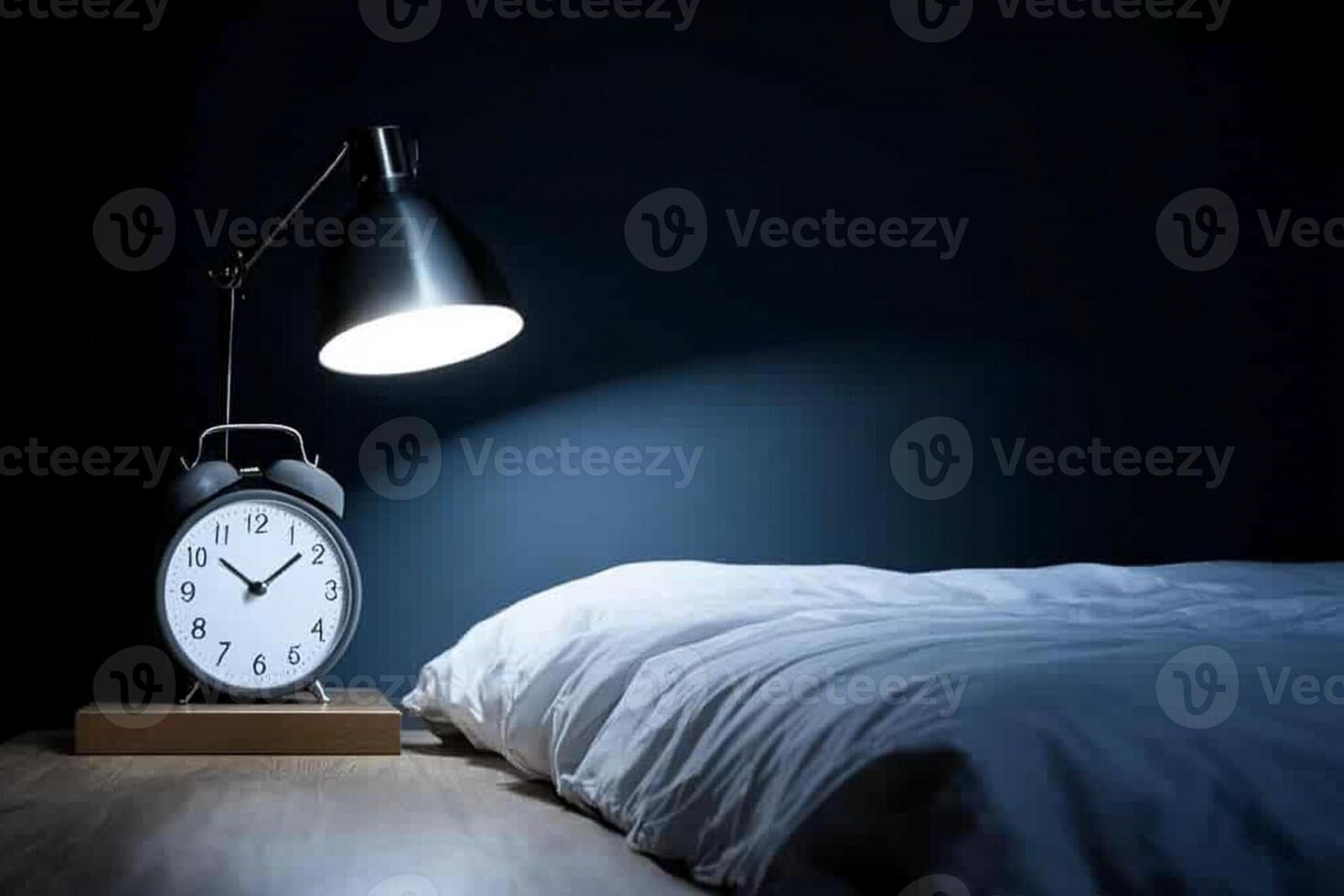 An alarm clock sits on a table next to a bed photo