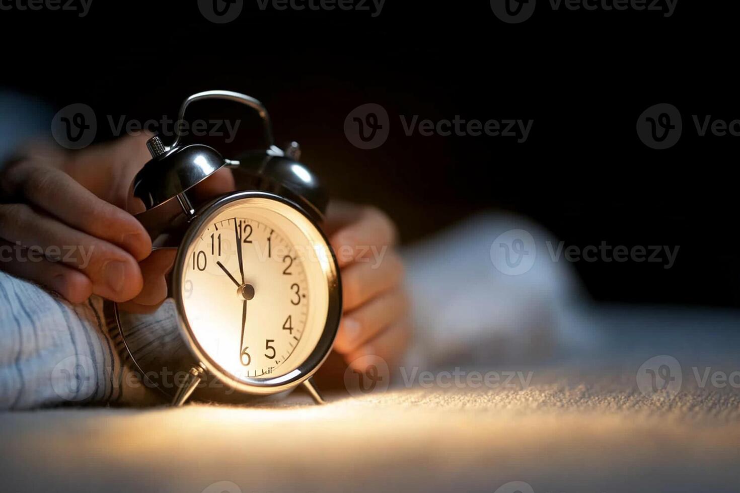 A person is holding an alarm clock in the dark photo