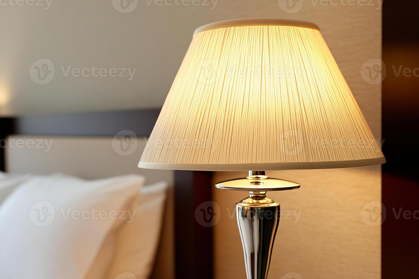 A lamp on a bed next to a white pillow photo