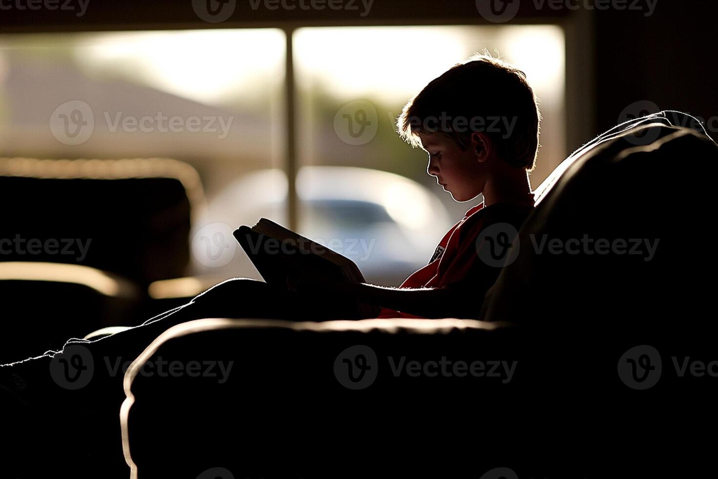 A boy sitting on a couch reading a book photo