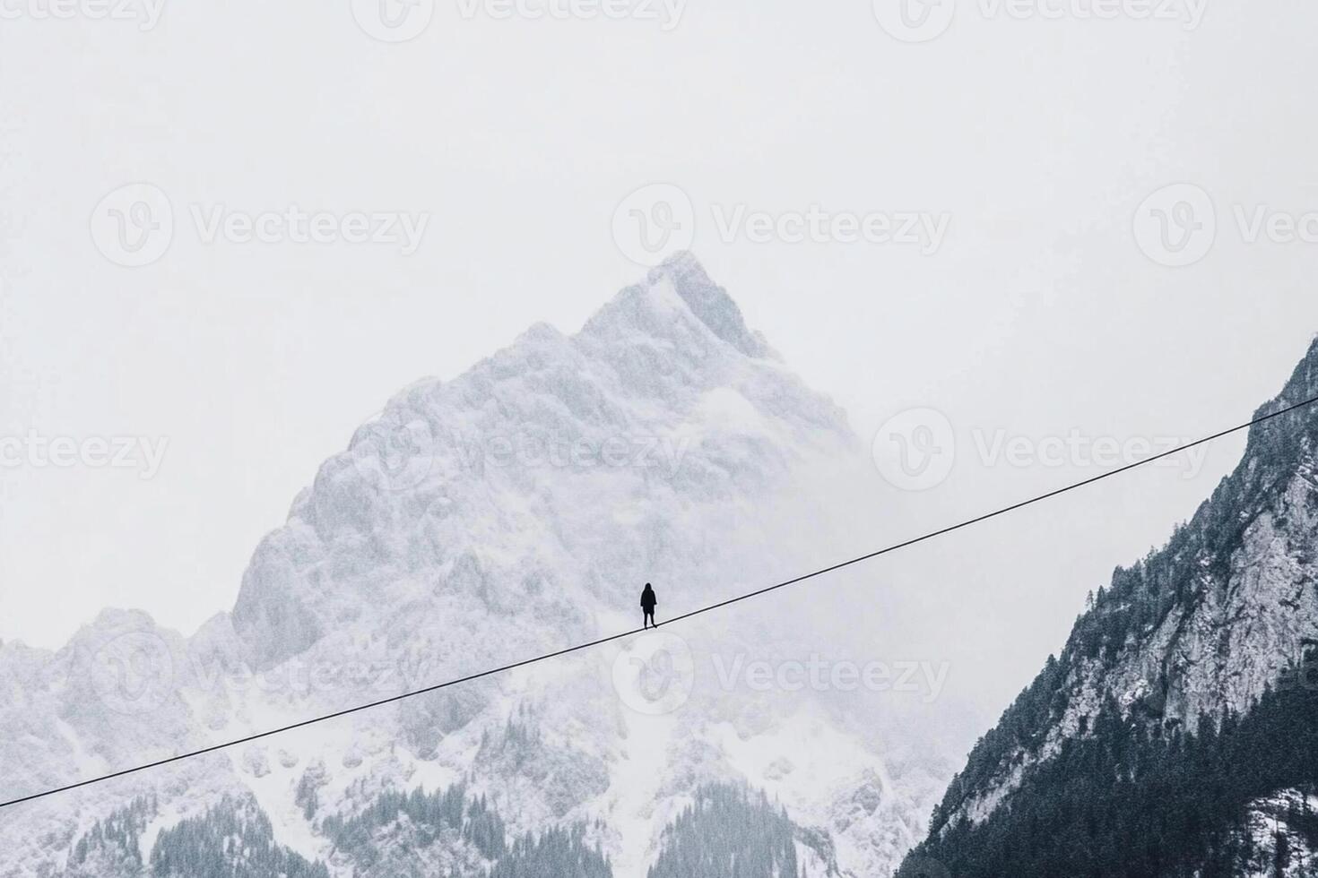 A person walking on a wire over a mountain photo