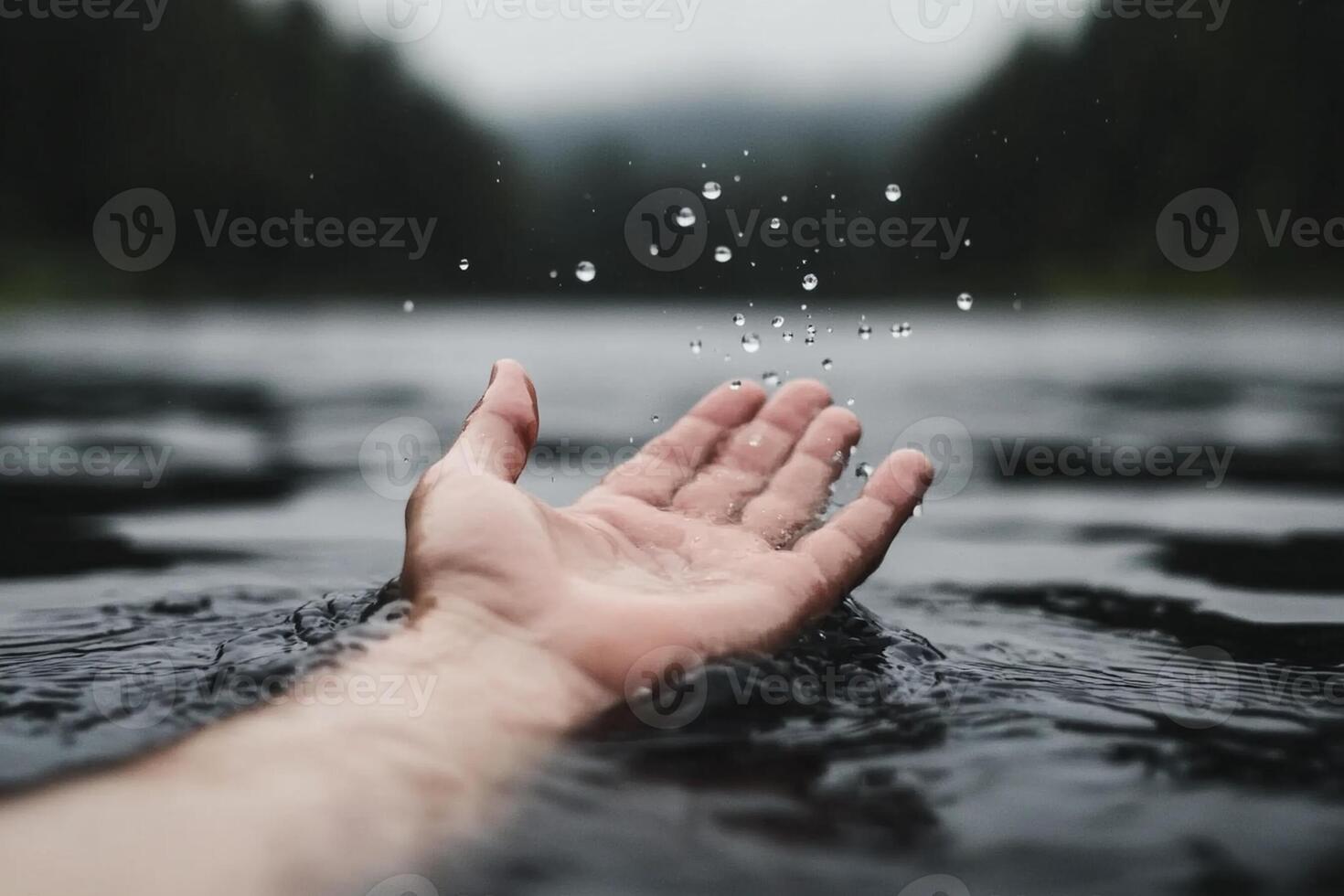 A person's hand reaching out to touch water photo