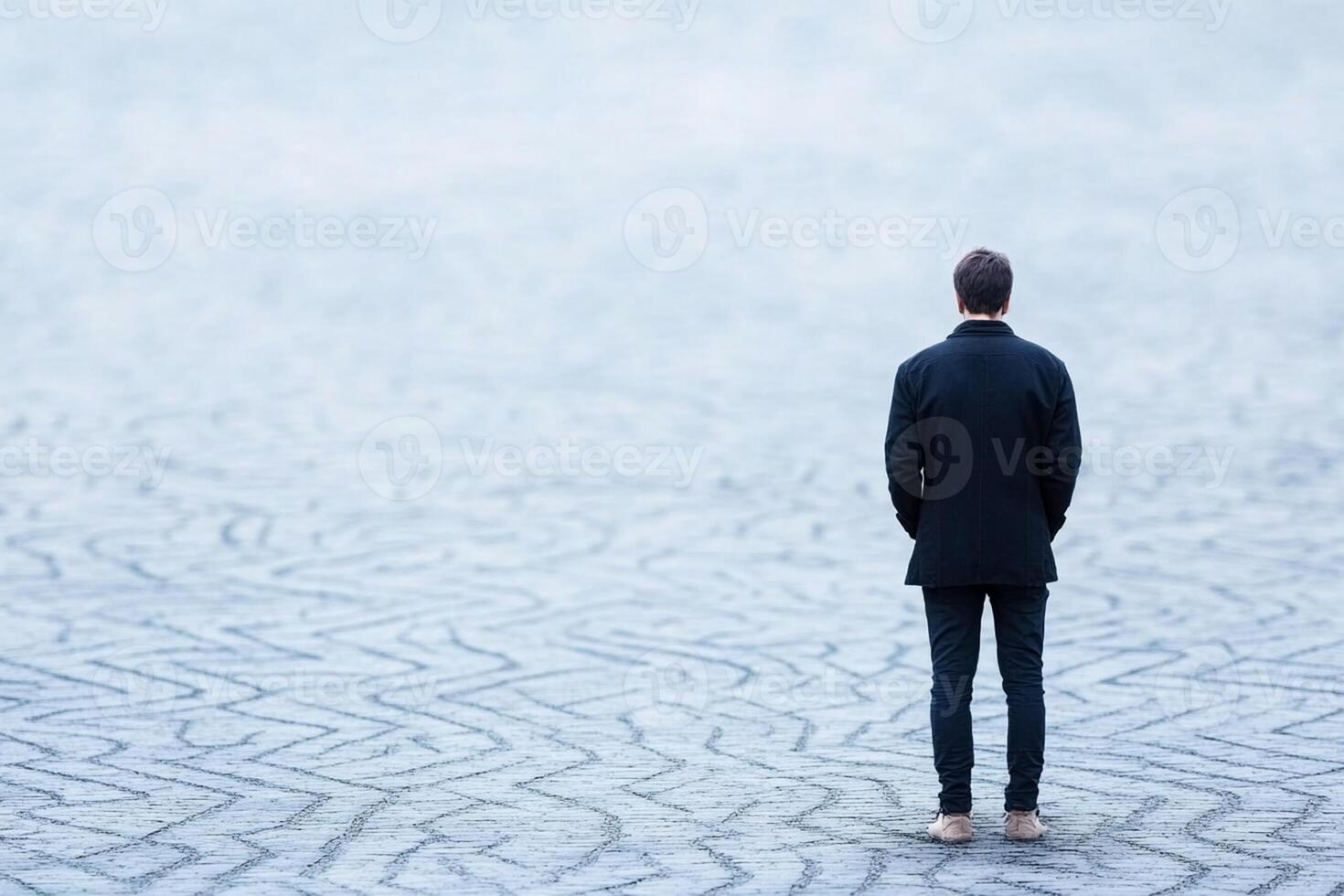 A man in a suit stands alone in the middle of a large field photo