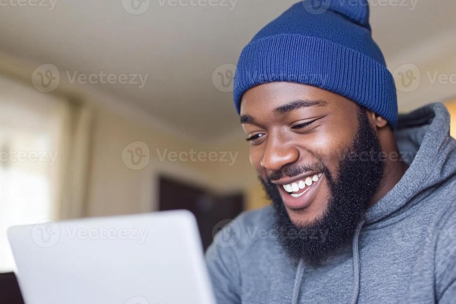 A man with a beard smiles while using a laptop photo