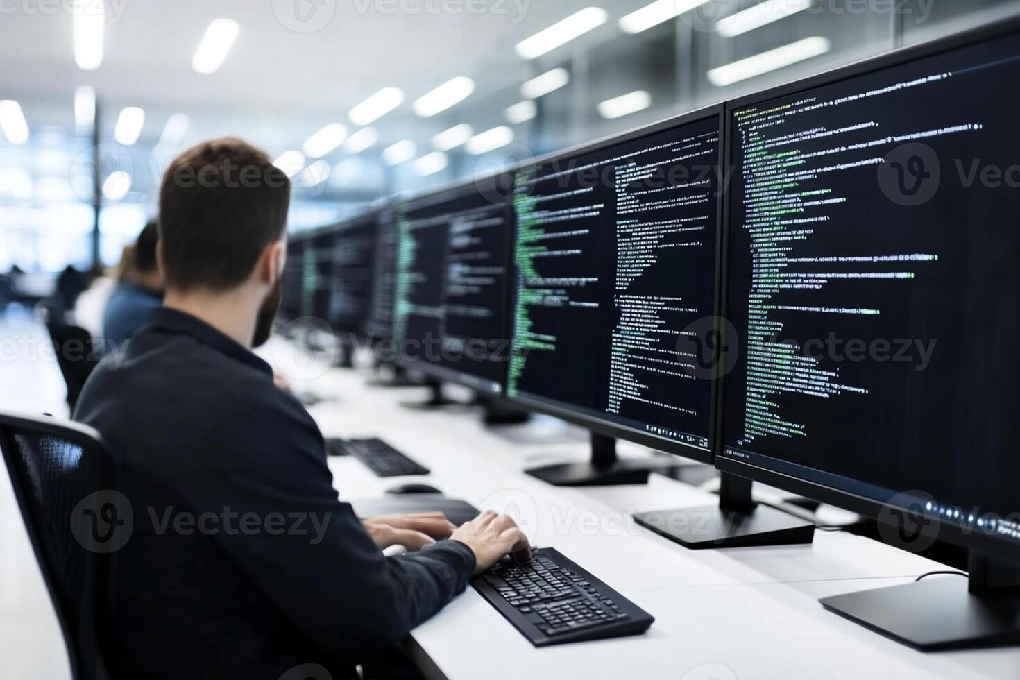 A man is working on a computer with several screens photo