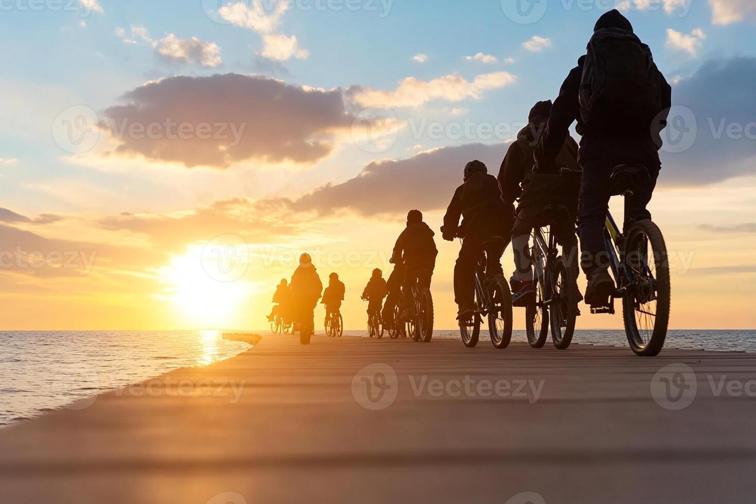 A group of people riding bikes on a pier at sunset photo