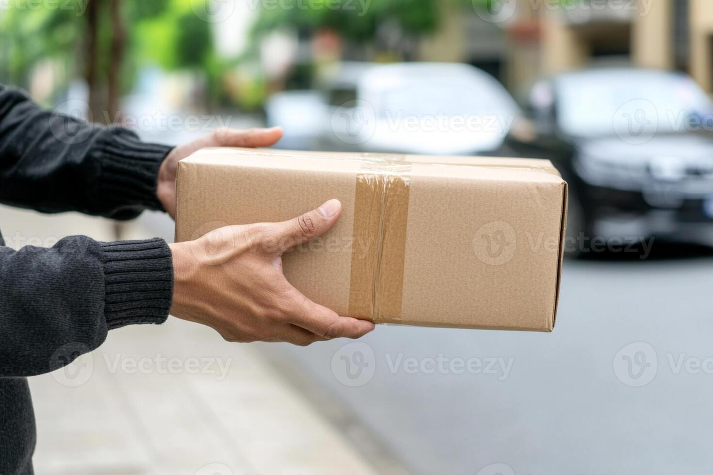 A man is holding a brown box on the street photo