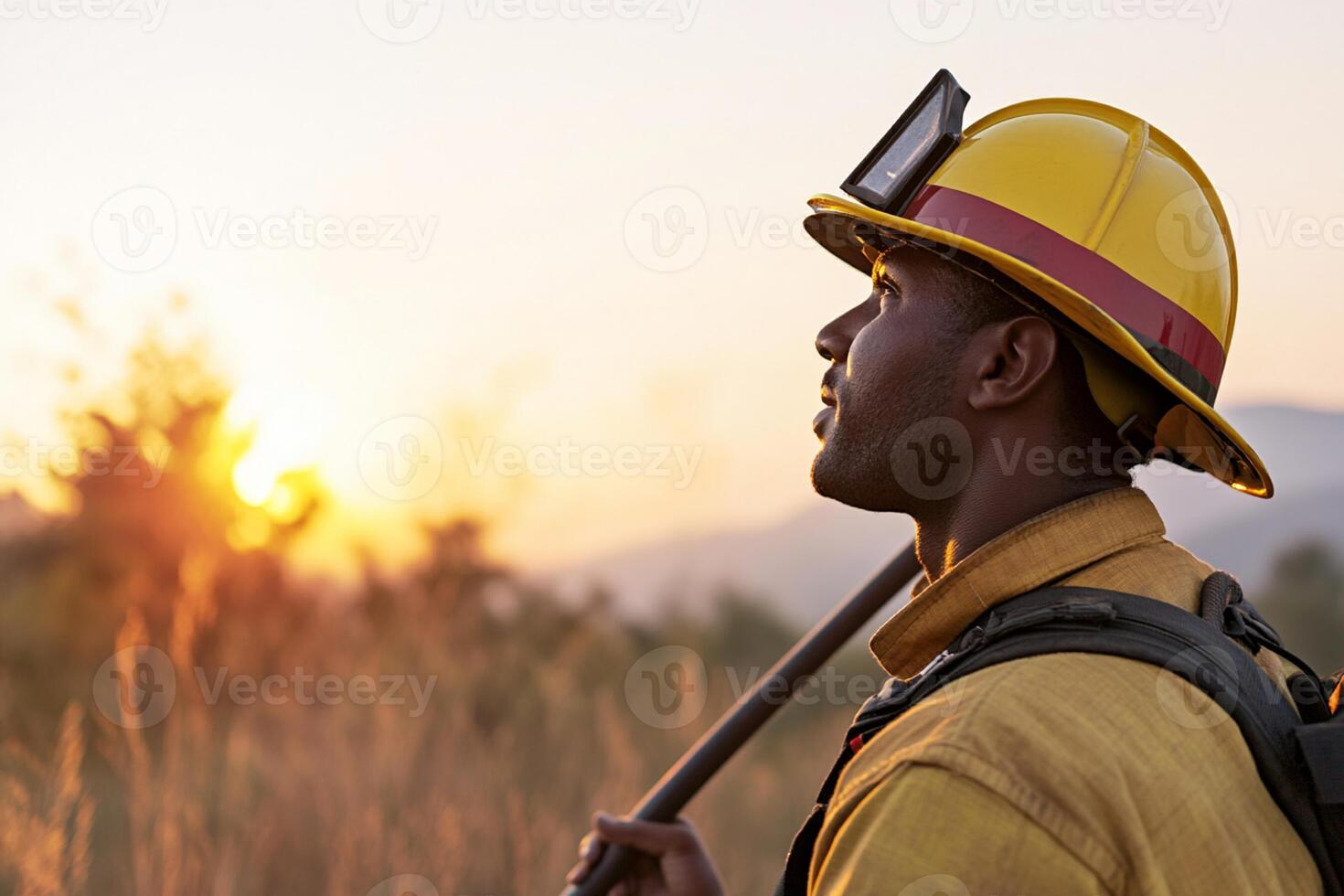 A firefighter with a hat and a stick in the grass photo