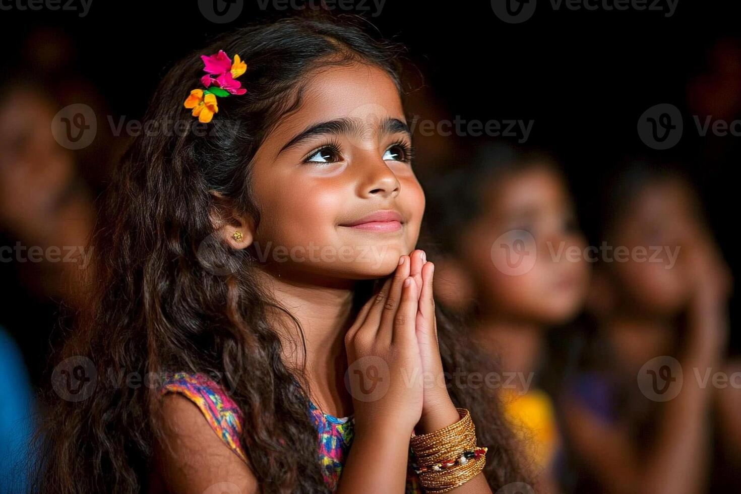 A little girl is praying in front of a crowd photo