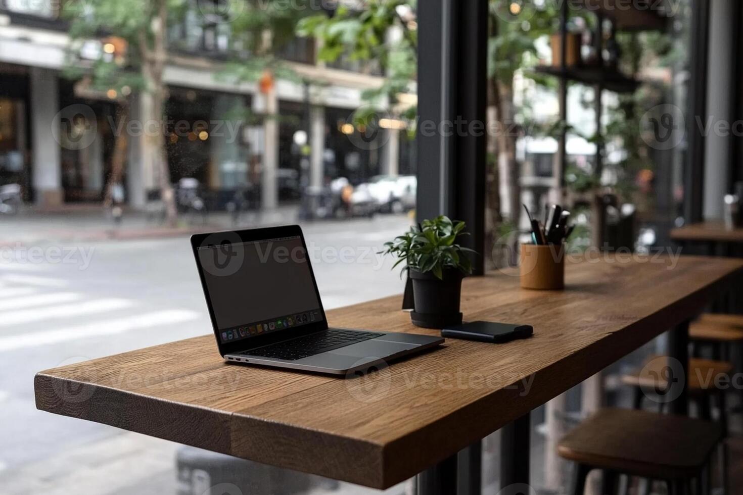 A laptop is sitting on a wooden table in front of a window photo