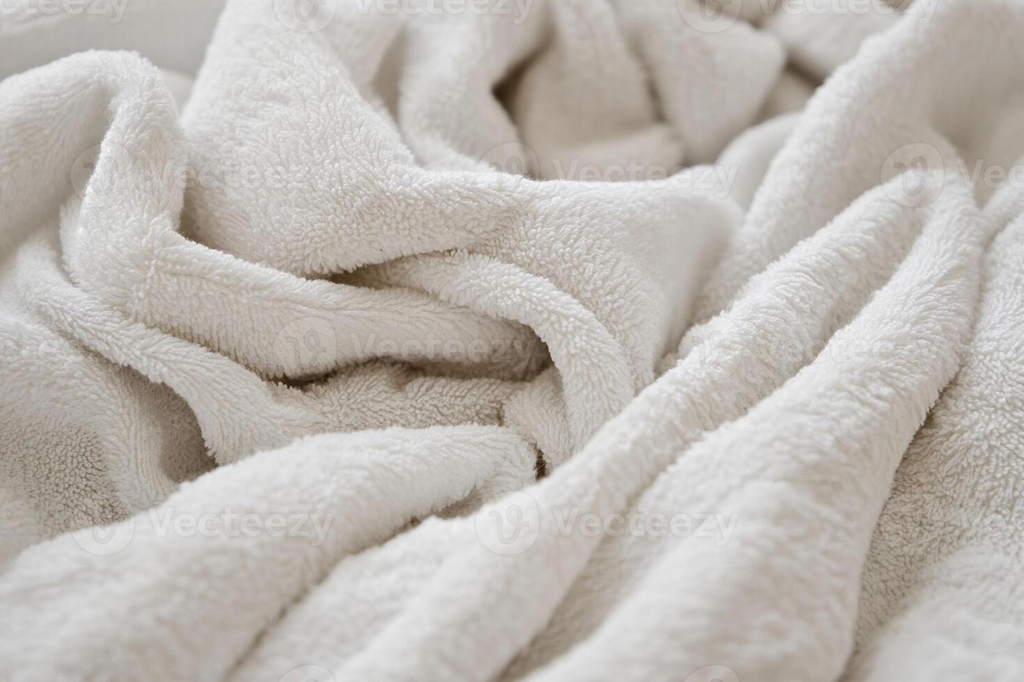 A white blanket is folded over a bed photo