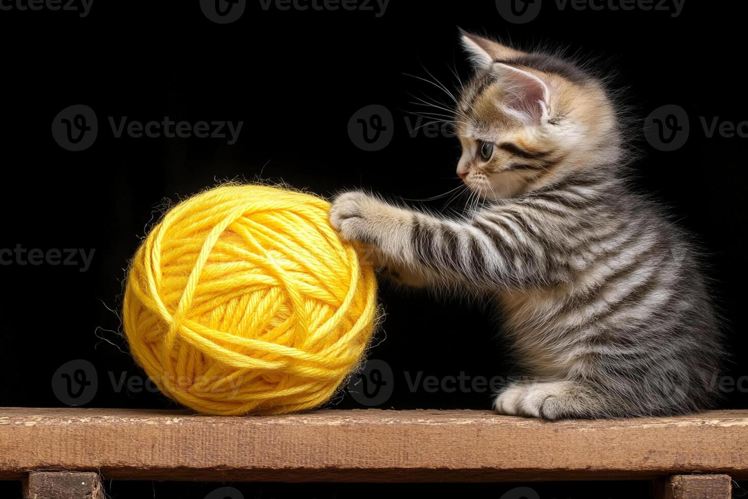 A kitten playing with a ball of yellow yarn photo