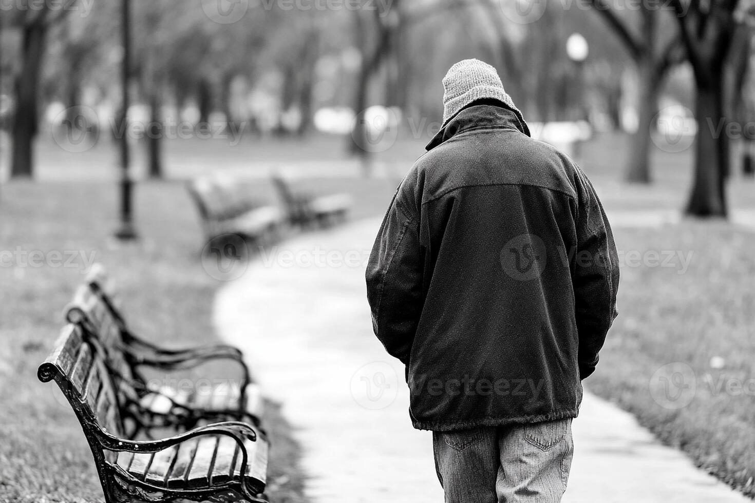 A man walking down a path with a park bench photo