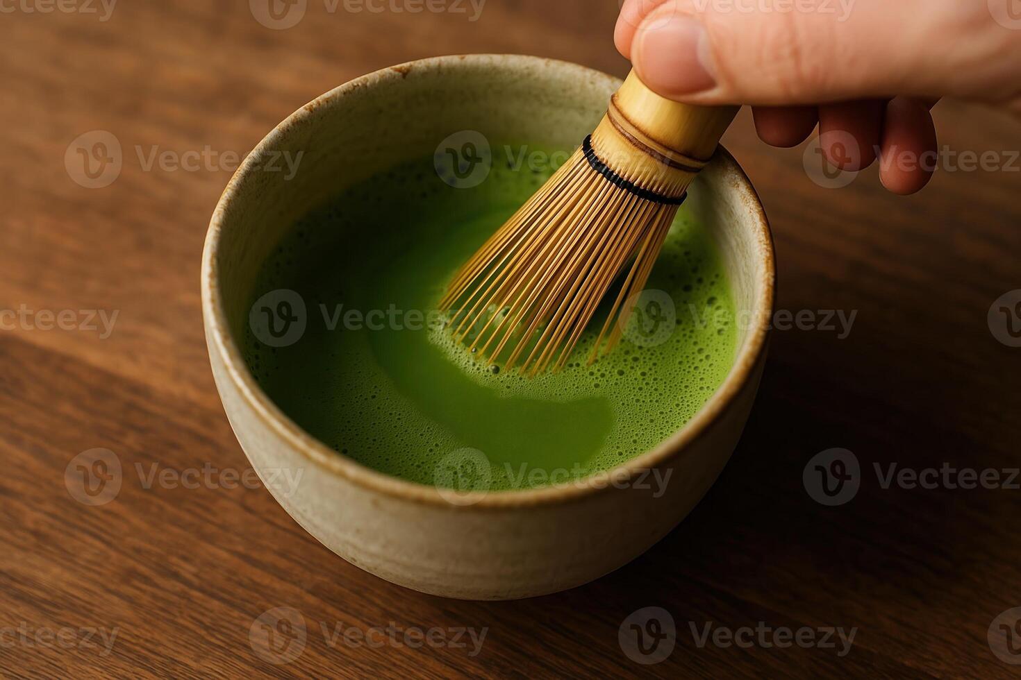 Preparation of Matcha Green Tea in Ceramic Bowl with Bamboo Whisk on Wooden Surface photo