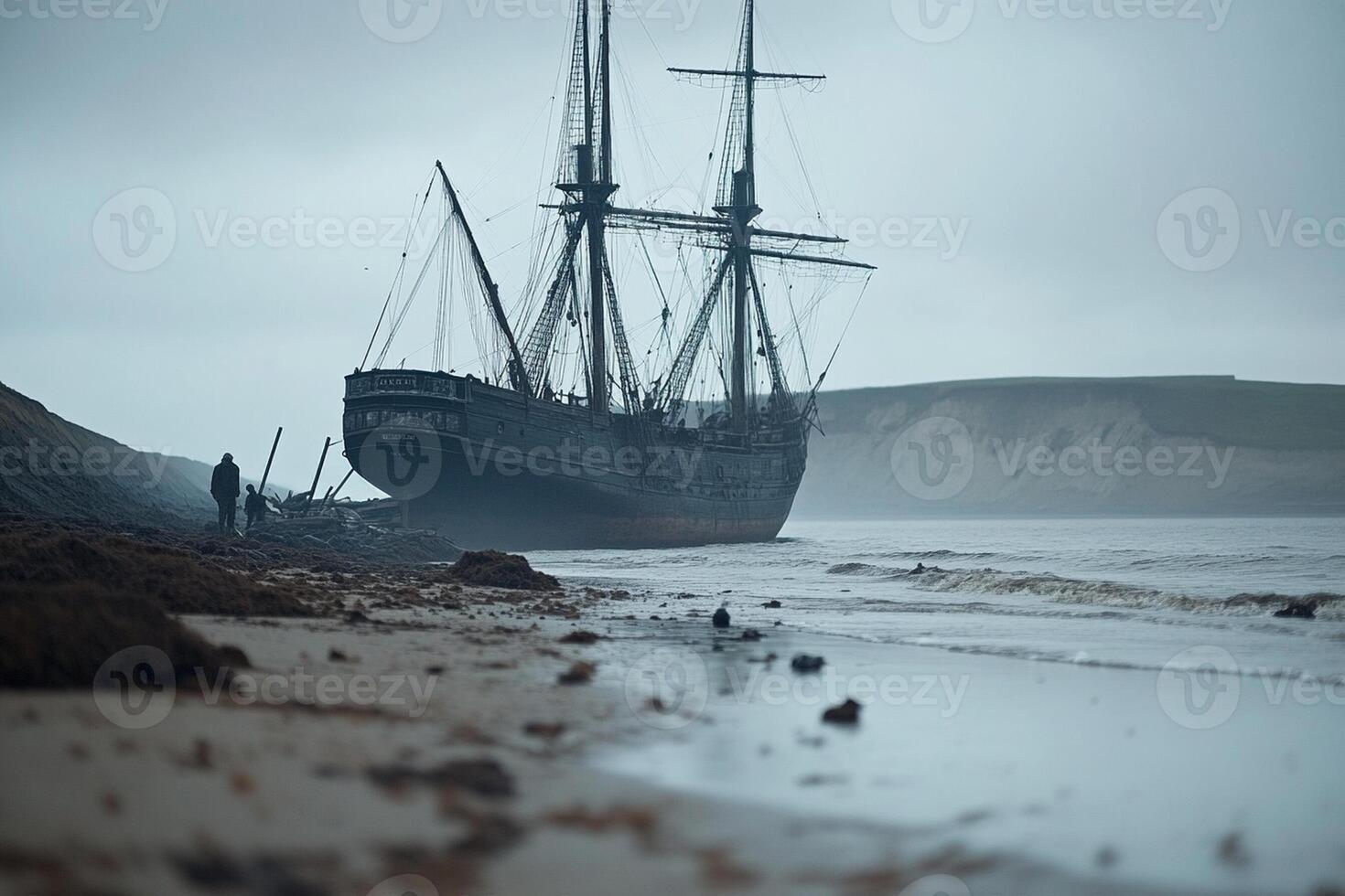 A man standing on the shore next to an old ship photo