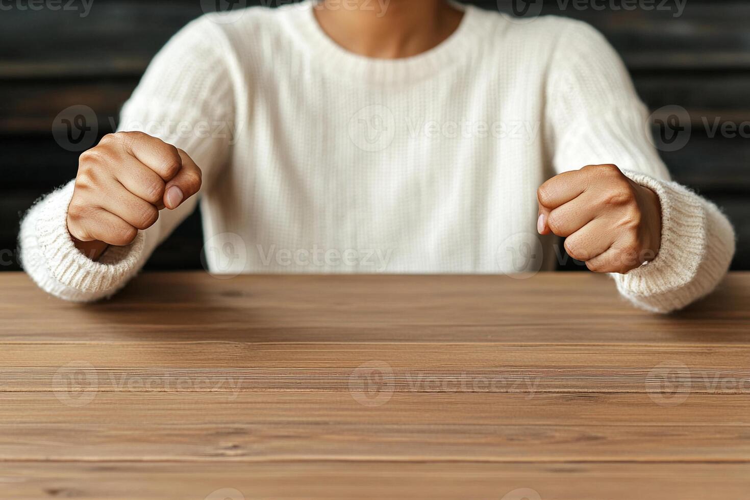 A woman is sitting at a table with her hands on it photo