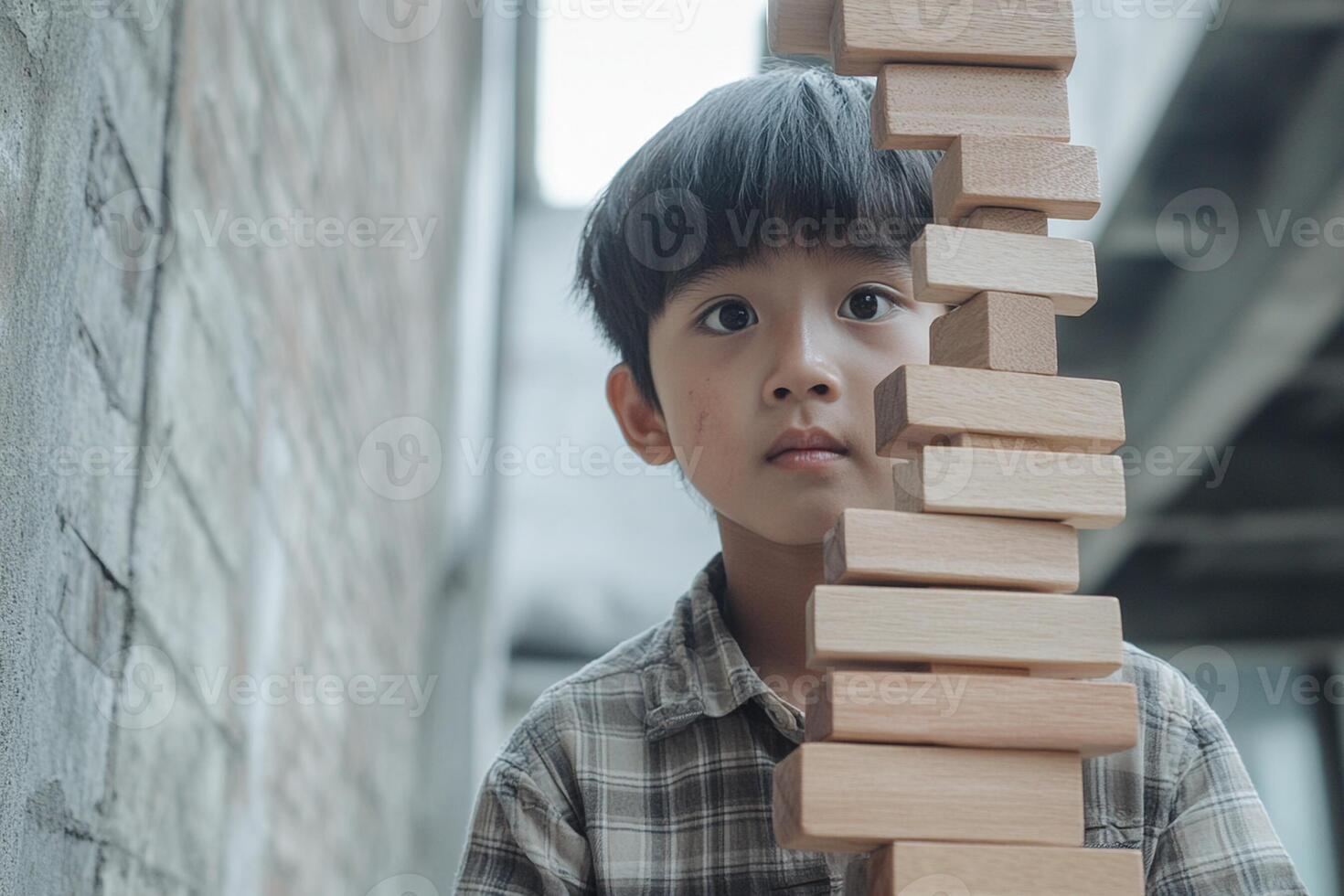 A young boy is standing in front of a stack of wooden blocks photo
