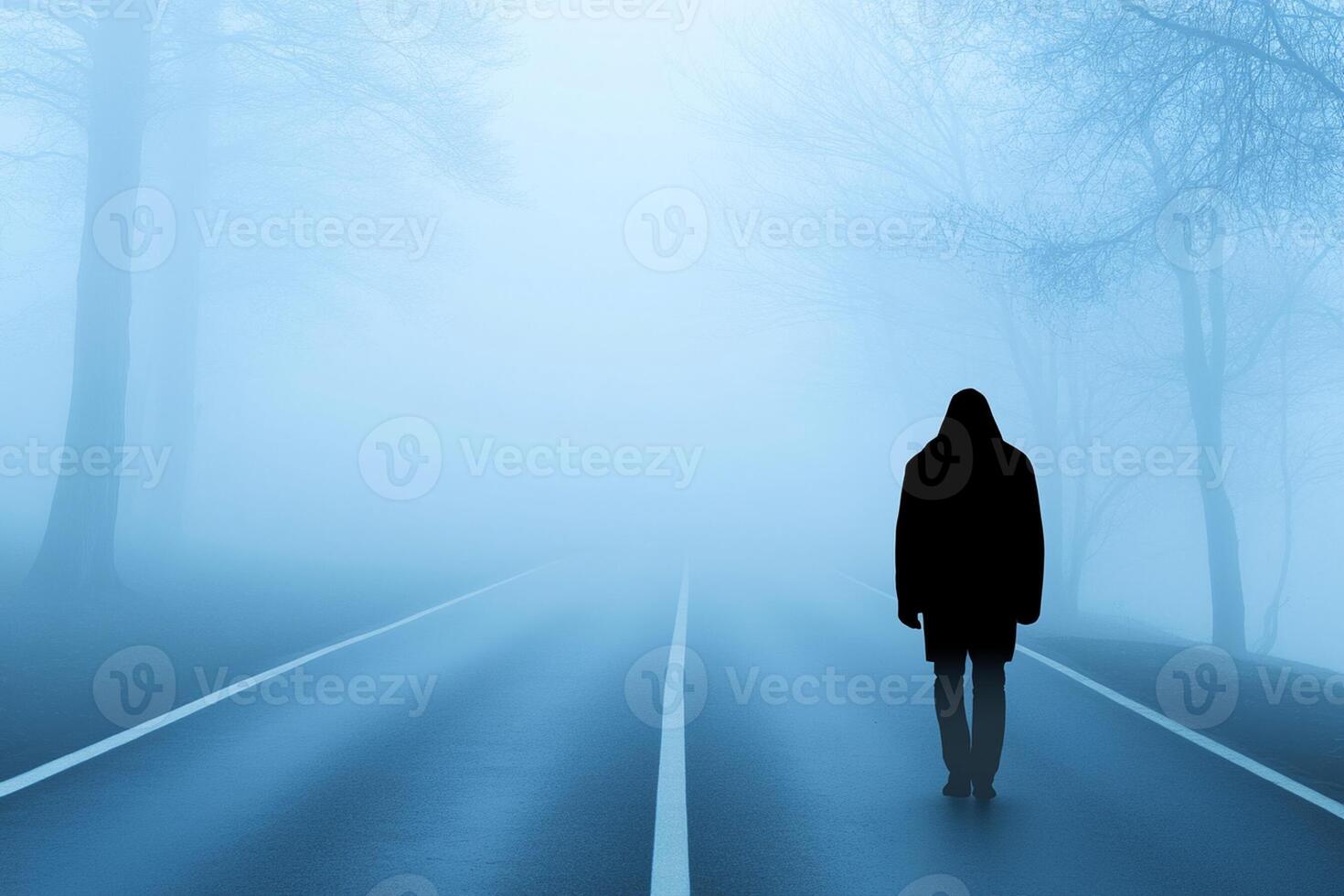 A person walking down a road in the fog photo