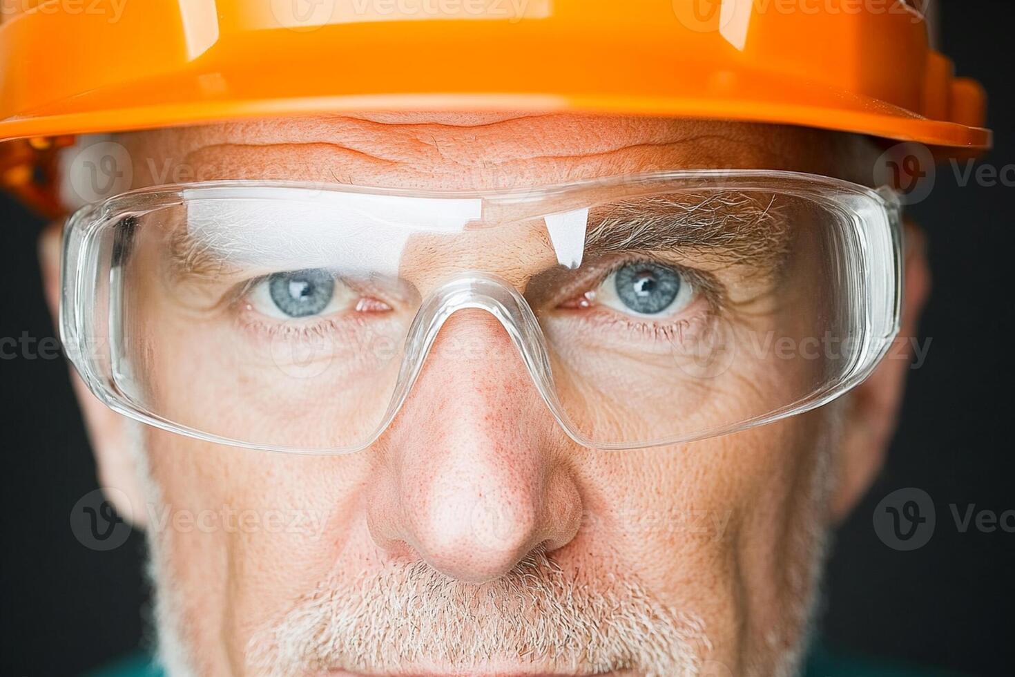 An older man wearing an orange hard hat and safety glasses photo