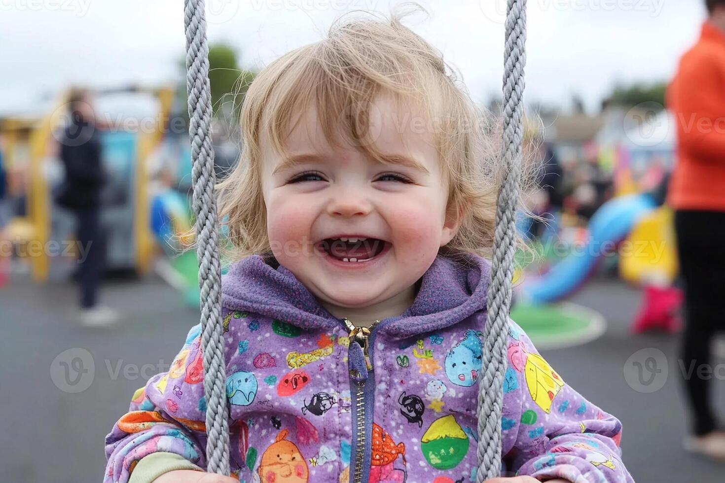 A smiling toddler on a swing at a playground photo