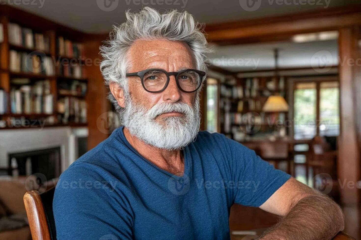 A man with a beard and glasses sitting in front of a bookcase photo