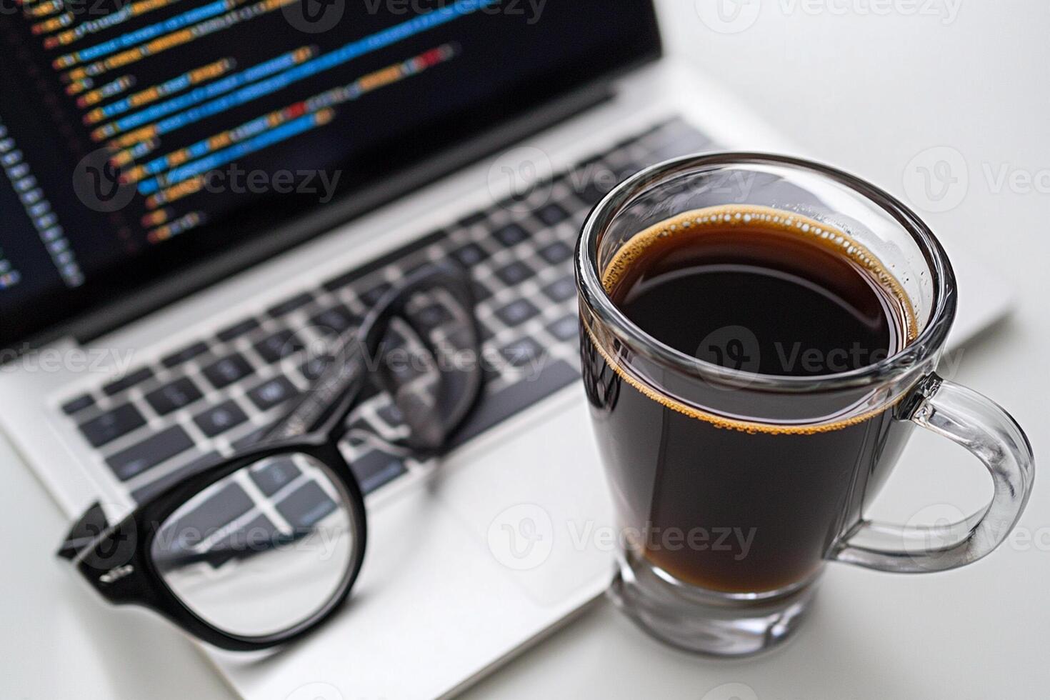 A cup of coffee and a laptop with a code on the screen photo