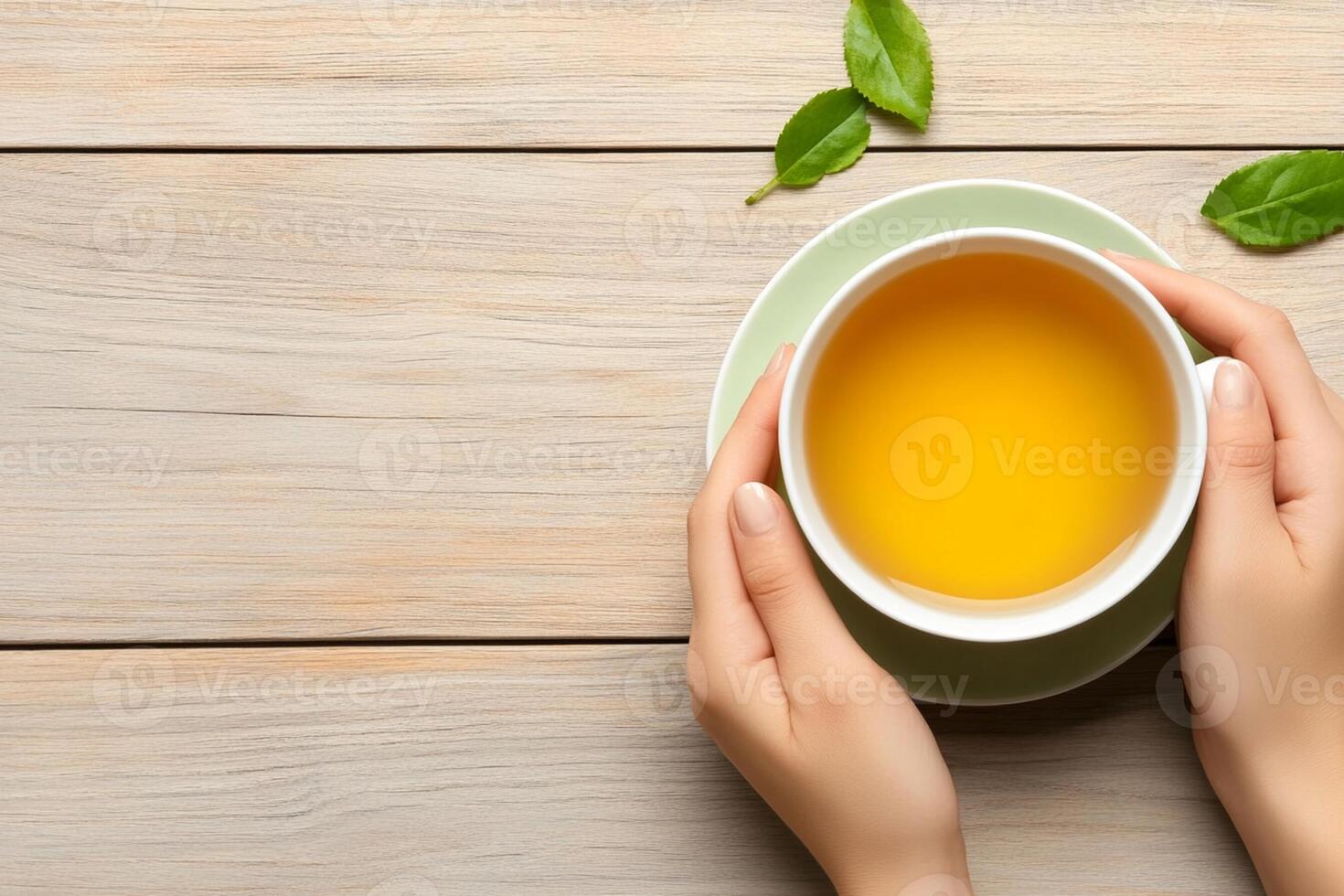 Woman's hands holding a cup of tea on wooden table photo