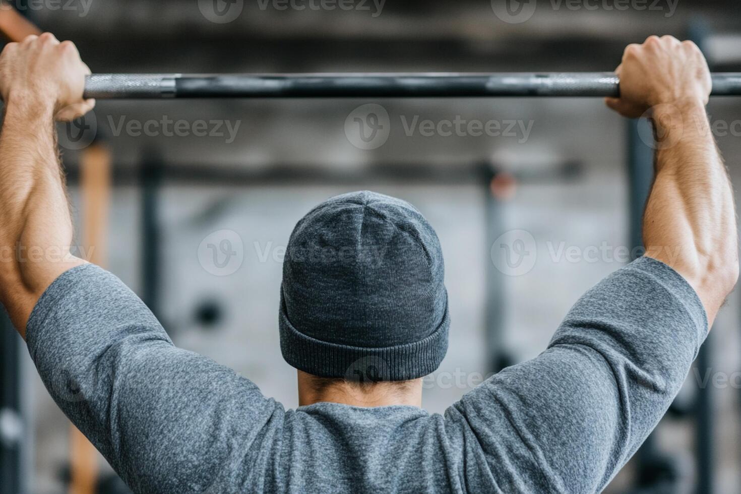 A man in a grey hat is holding a barbell photo
