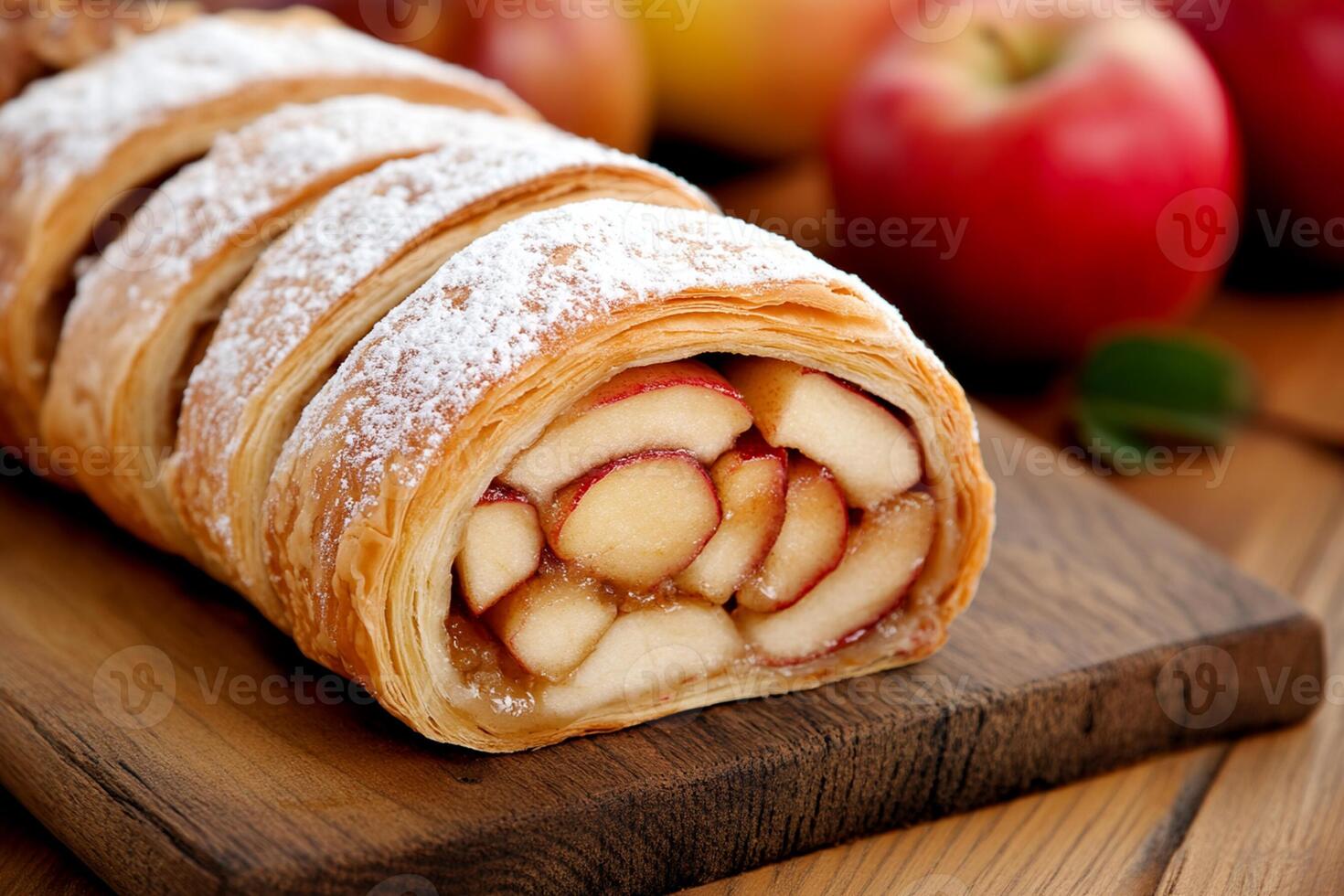 A pastry with apples and powdered sugar on a wooden cutting board photo