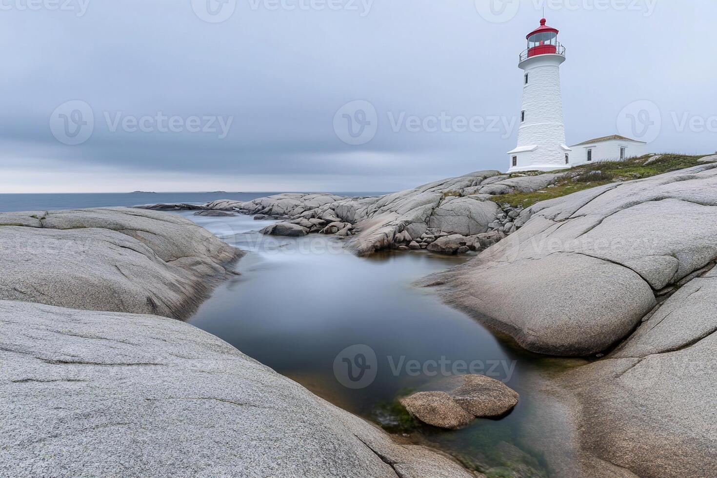 A lighthouse sits on the rocky shoreline of a body of water photo