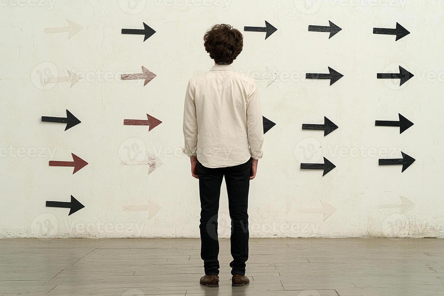 A man standing in front of a wall with arrows pointing in different directions photo