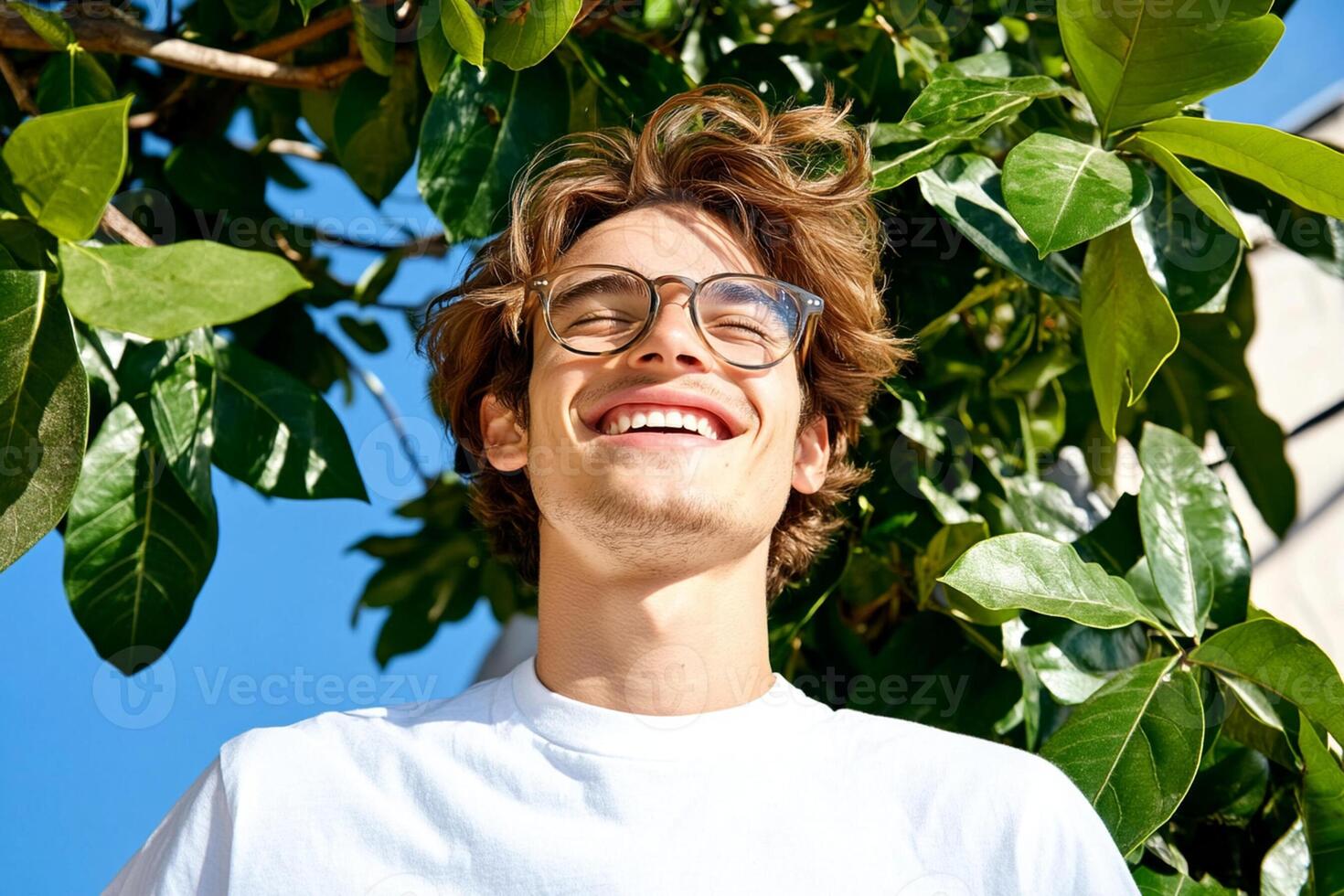 A man with glasses and a white t - shirt is smiling photo
