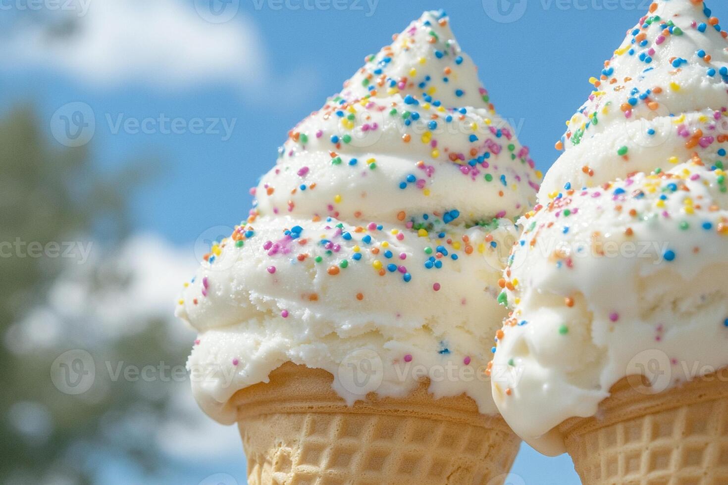 Two ice cream cones with white frosting and sprinkles photo