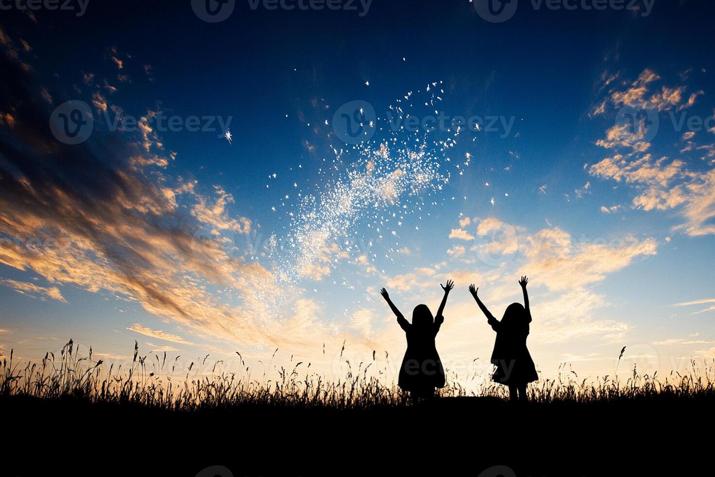 Two girls standing in the grass with their hands up in the air photo