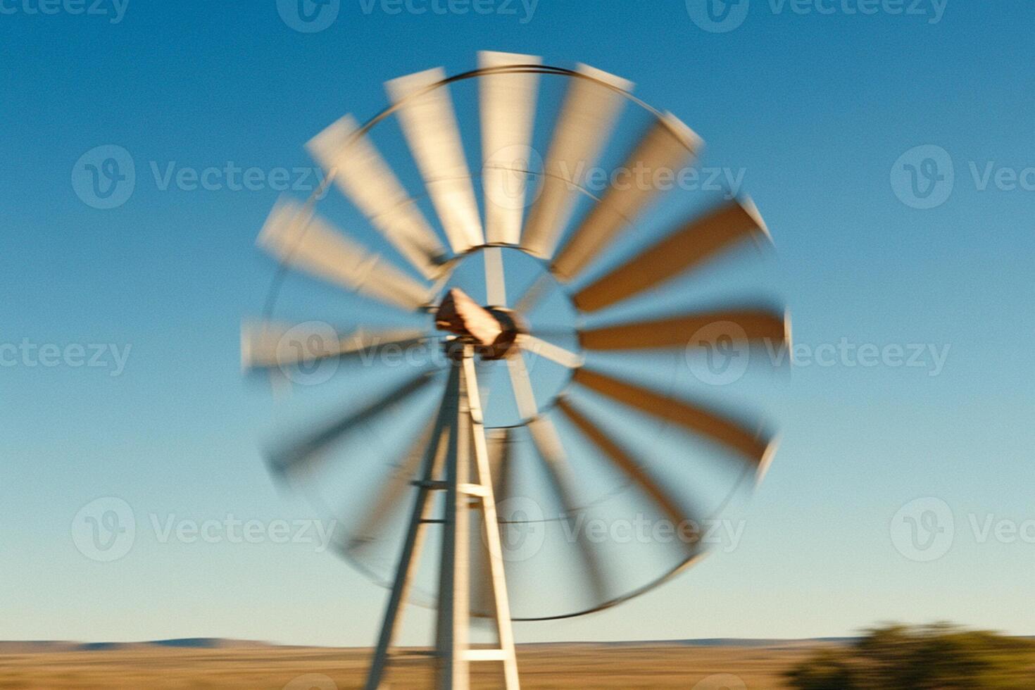 A windmill is spinning in the middle of a field photo
