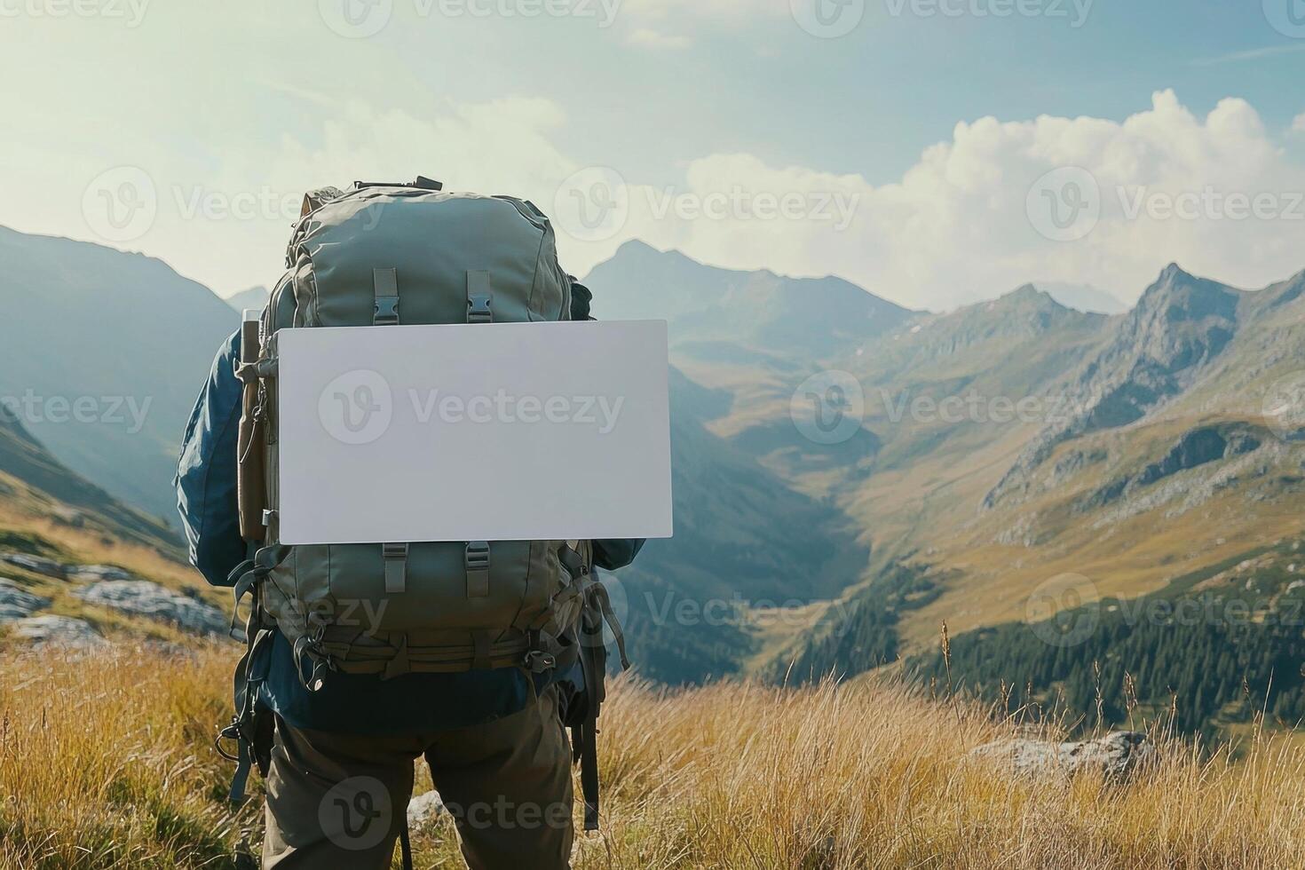 A man is standing on a mountain with a white sign on his back photo