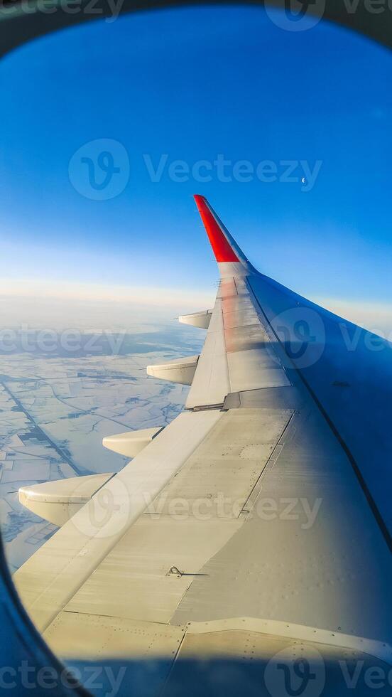Flying on an airplane. The wing of an airplane flying over clouds with a sunset sky. View from the airplane window. photo