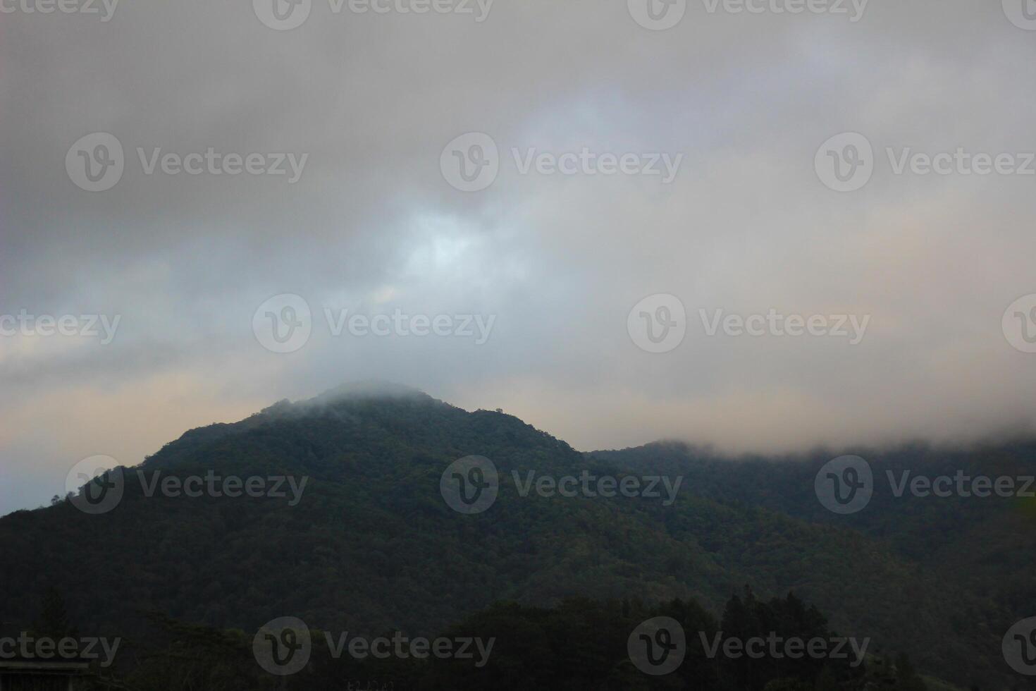 A breathtaking mountain valley with green hills, scattered houses, and misty clouds, showcasing the beauty photo