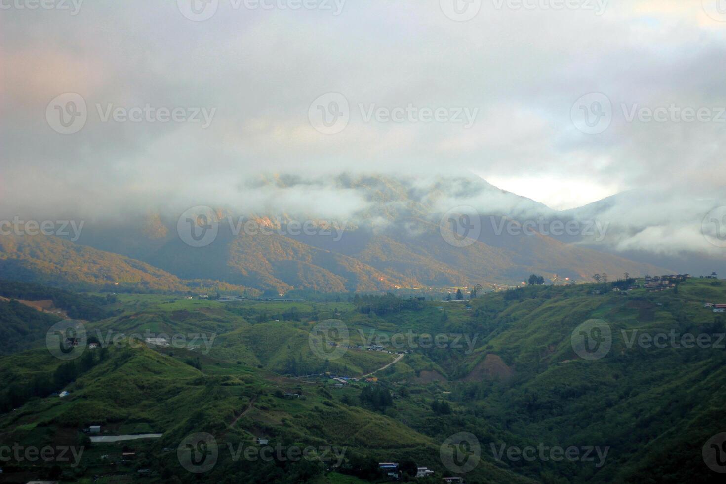 Majestic Green Mountains Covered in Morning Mist with Rural Villages and Cloudy Sky photo