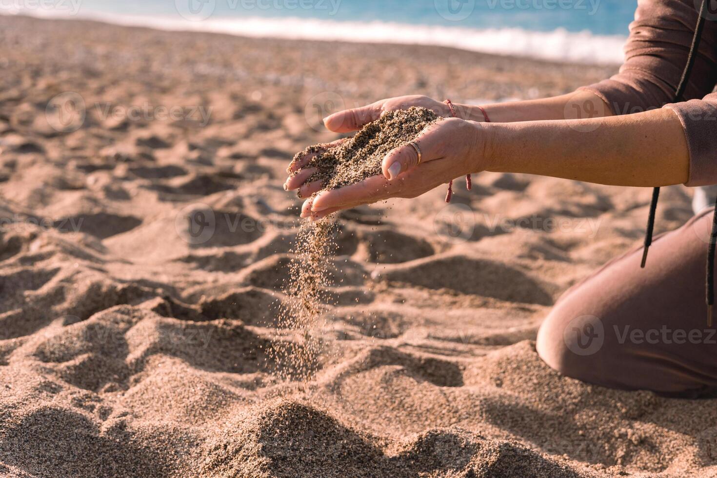 Hands releasing beach sand during sunset on a tranquil shoreline photo
