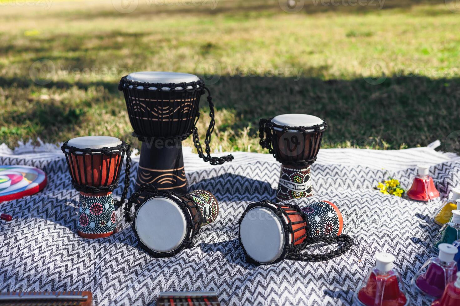 Colorful hand drums displayed on a blanket in a sunny park setting near picnic items photo