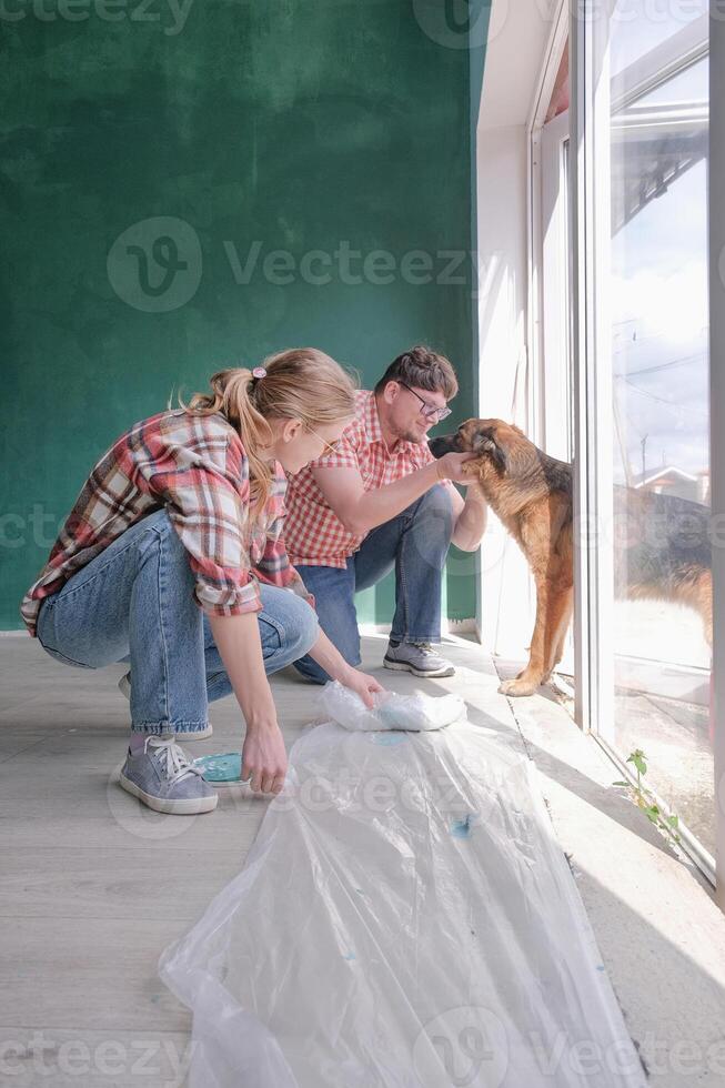 Happy couple renovating house apartment , putting protective film on the floor . Family man woman repair flat themselves. photo