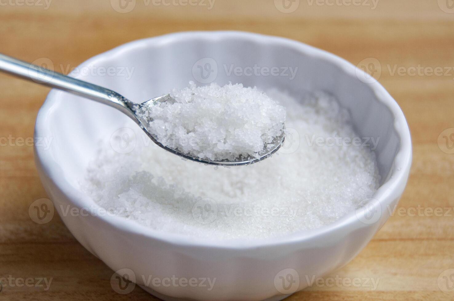 Side view of a spoon filled with coarse salt with customizable space for text or ideas. photo